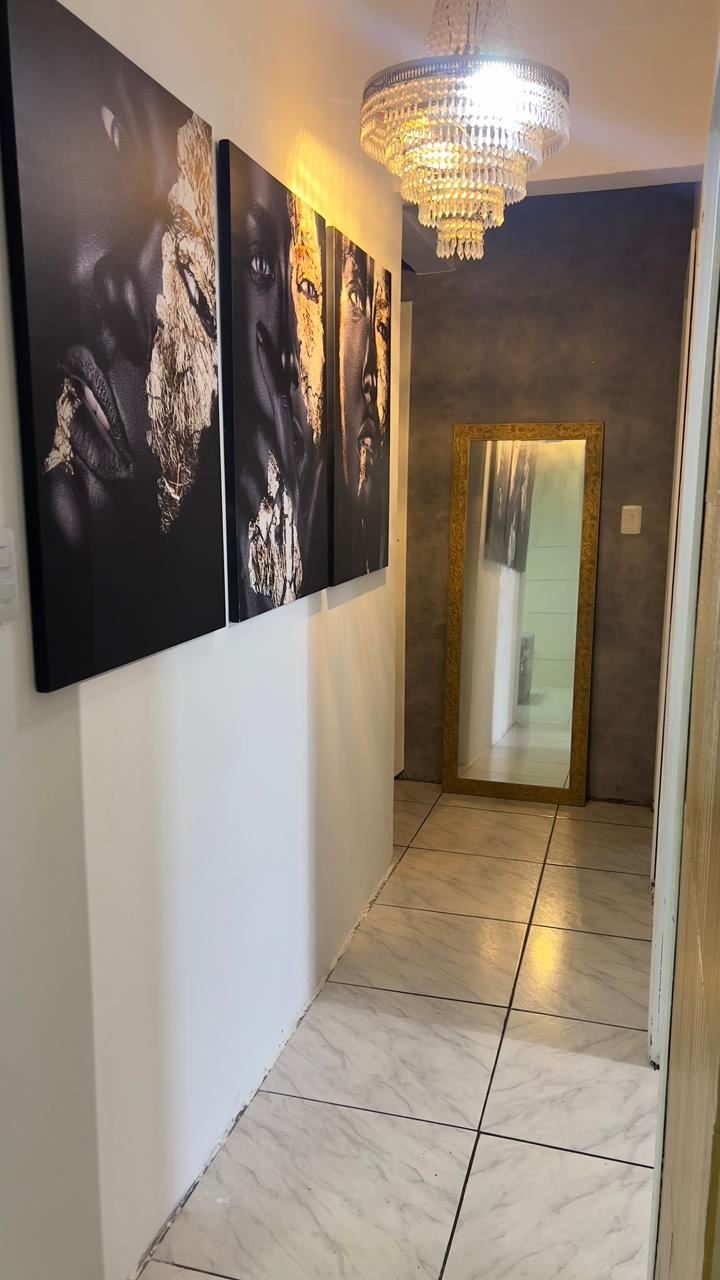 Corredor decorado com quadros, lustre de cristal e espelho de moldura dourada
